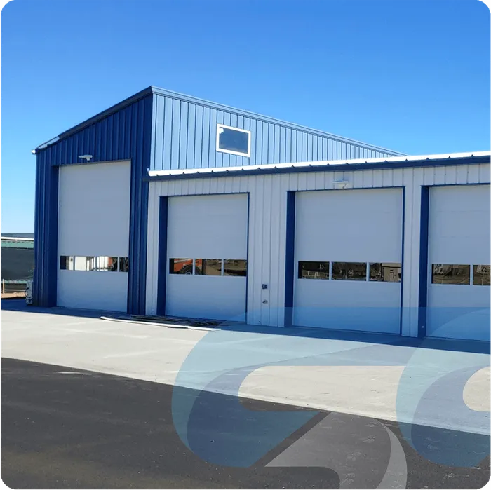 Blue and white metal building with three garage doors and a clear sky.